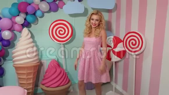 一个穿着粉红色条纹连衣裙穿着大糖果的快乐女孩的肖像视频的预览图