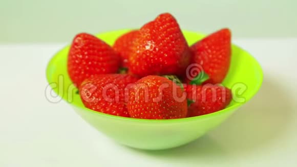 蓝色背景上绿色盘子里的红色新鲜草莓旋转成一个圆圈视频的预览图