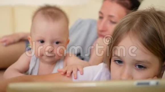 家庭观念姐姐和弟弟在房间的沙发上用平板电脑充满爱意的家庭年轻母亲视频的预览图