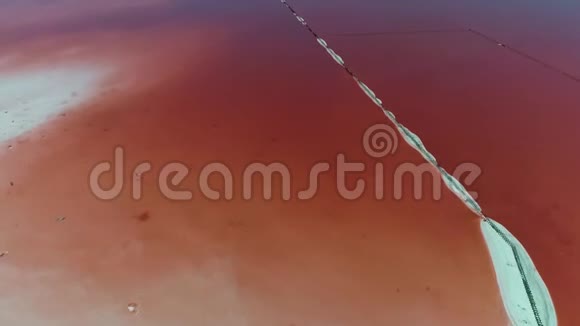 从高处看粉红色咸湖之间狭窄的沙路视频的预览图