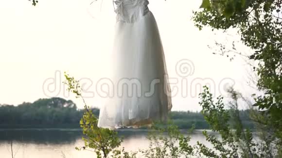 白色手工休闲婚纱挂在花园的树枝上视频的预览图