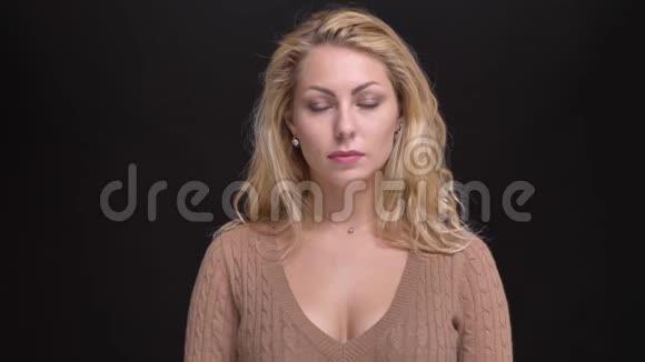 美丽的白种人长发女子在黑色背景下平静地观看镜头的肖像视频的预览图