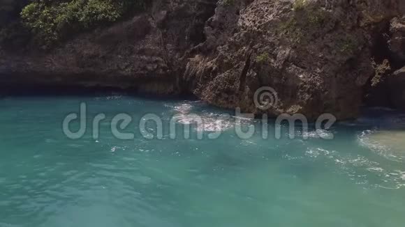 蓝色海水和岩石悬崖景观海浪溅起泡沫喷向悬崖山青绿色海洋视频的预览图