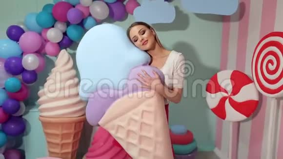 一个可爱的女孩拿着一个巨大的冰淇淋在工作室的背景上巨大的糖果视频的预览图
