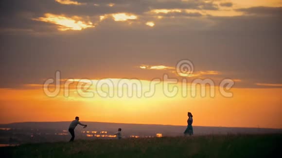 年轻的父母和他们的小儿子玩得很开心妈妈带着孩子到处跑一个灿烂的日落一个夏日的傍晚视频的预览图