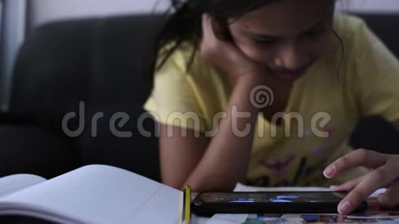 小女孩在做作业时使用手机视频的预览图