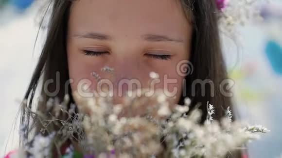 女孩的特写肖像她的脸嗅着花慢慢地视频的预览图