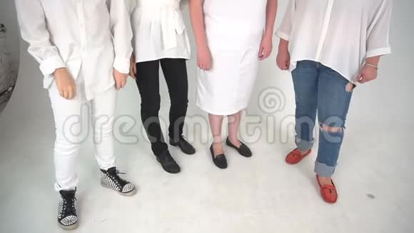 四个人穿着牛仔裤连衣裙皮裤站在地板上孤立的白色背景视频的预览图