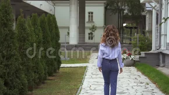 黄色动作一个长着棕色卷发的年轻漂亮女孩正走在公共花园的小径上视频的预览图