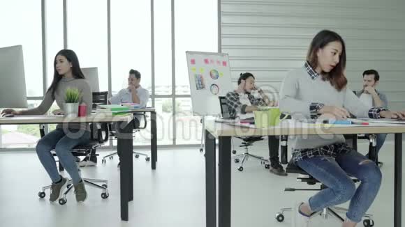 一群快乐快乐的亚洲创意企业男女在她的办公室工作时喜欢跳舞并玩得很开心视频的预览图