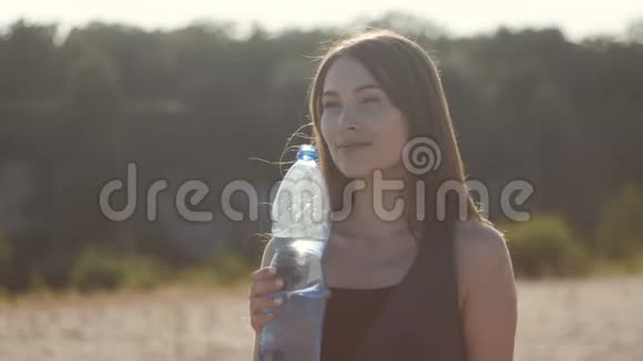 小可爱的女人在炎热的夏天从大自然中的塑料瓶里喝水女孩渴望喝水视频的预览图