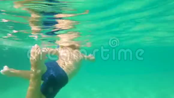 4k水下拍摄一个可爱的小男孩带着面具和管子在热带海洋中潜水有很多热带鱼视频的预览图