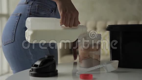 年轻的女人把牛奶倒进摇床在家里摇一摇视频的预览图