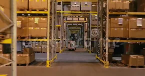 叉车在仓库里搬运装有产品的箱子叉车在仓库的两排之间行进视频的预览图