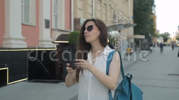 年轻女子站在街上正在用电话拍照视频的预览图