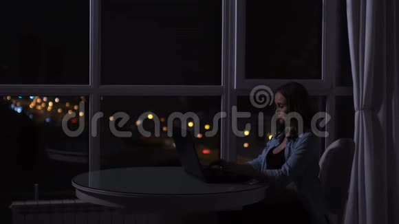 一位孕妇在电脑上工作得很晚夜晚坐在电脑前的一扇大窗户前可以看到视频的预览图