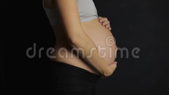 孕妇抚摸她的腹部慢动作暗背视频的预览图