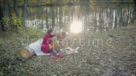 快乐年轻的一家人在湖边野餐视频的预览图