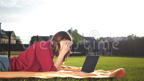 一个戴眼镜的少女进入她的信用卡号码一台笔记本电脑一个后院视频的预览图