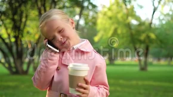 小女孩在公园里边打电话边喝咖啡视频的预览图