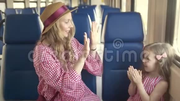 年轻的母亲和小女儿坐在空火车的窗前玩蛋糕视频的预览图