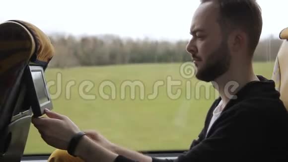 年轻人坐在公共汽车上看着座位最靠前的监视器视频的预览图