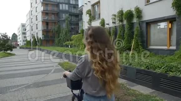 晴天骑自行车的年轻女子城市里骑自行车的年轻女子或女孩的美丽心情照片长着一头黑发的女孩视频的预览图