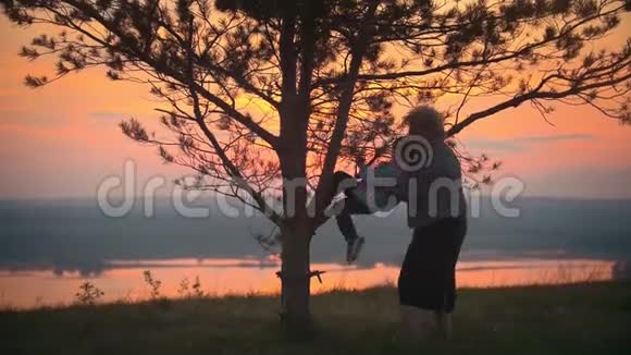 奶奶和孙子在夏日夕阳下玩耍奶奶帮孙子爬树视频的预览图