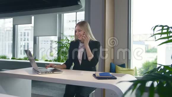 时髦的商务女性看笔记本电脑和打电话时尚的金发女郎在餐桌上工作视频的预览图