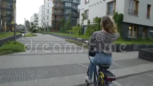 晴天骑自行车的年轻女子城市里骑自行车的年轻女子或女孩的美丽心情照片长着一头黑发的女孩视频的预览图