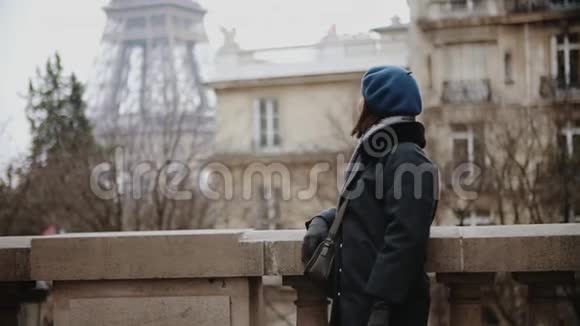 穿着贝雷帽和外套的时髦女人在巴黎埃菲尔铁塔边四处张望视频的预览图
