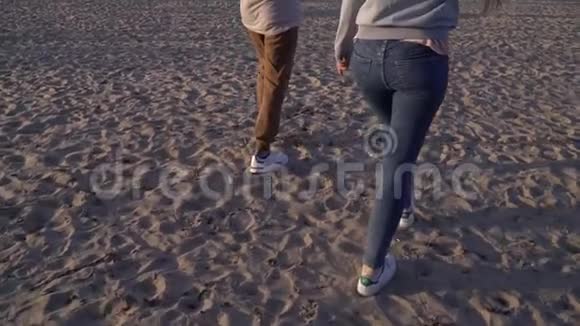 在河流和城市的背景下一个女孩和一个男孩沿着海滩散步视频的预览图