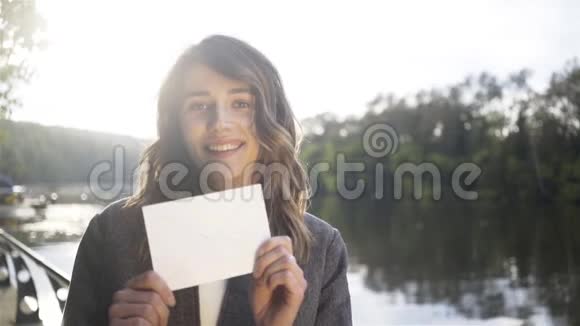 一位年轻女子在河边展示信封视频的预览图