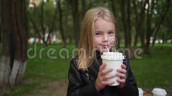 可爱的小女孩在公园里喝汽水视频的预览图