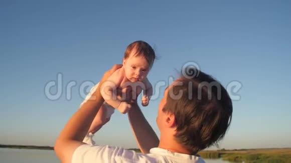 父亲抱着孩子在蓝天的映衬下亲吻脸颊视频的预览图