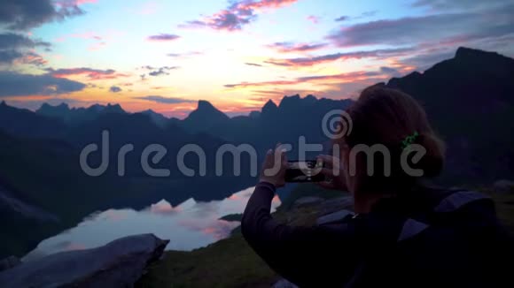 年轻女子拍摄日落背景山视频的预览图