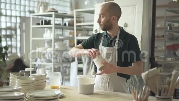 少爷在桌陶车间把杯子浸入液体中视频的预览图