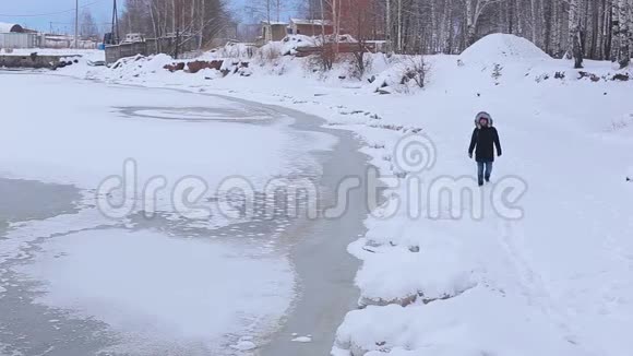 冬天年轻人在冰雪覆盖的冰冻河岸上视频的预览图