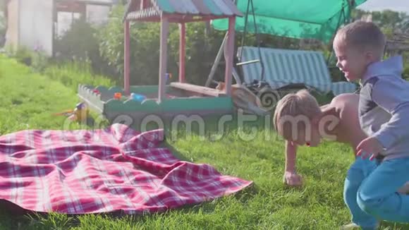 两个孩子在炎热的夏天在草坪上玩耍孩子们笑着他们跑着落在草坪上户外娱乐视频的预览图