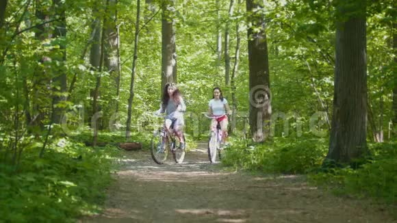 骑自行车在公园散步两个骑自行车的人家庭阳光明媚的一天前面的景色视频的预览图