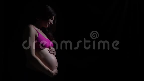 孕妇站在黑暗中抚摸着她的胃慢动作视频的预览图
