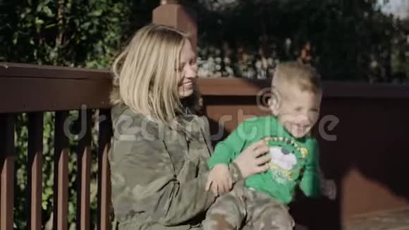 美丽的年轻母亲和儿子坐在公园的长凳上视频的预览图