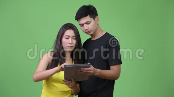 年轻的亚洲夫妇使用数码平板电脑看起来很震惊视频的预览图