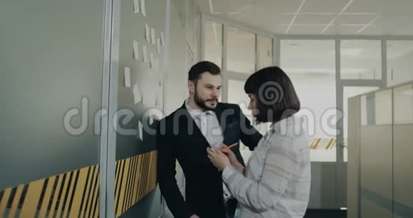 两个同事男人和女人做笔记并贴在墙上的办公室上视频的预览图