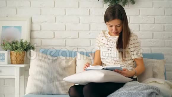 一个女孩坐在蓝色沙发上看书视频的预览图