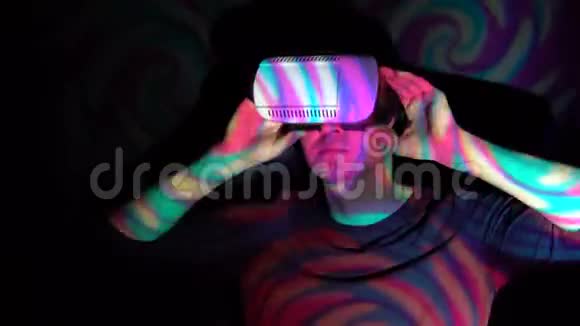 一个男人在聚光灯下用VR头盔看虚拟现实视频的预览图