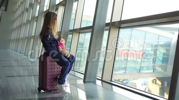 可爱的小女孩带着行李在机场等待登机望着窗外视频的预览图