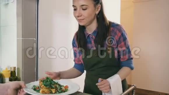 一个女服务员从餐厅的厨房拿着一盘白色盘子视频的预览图