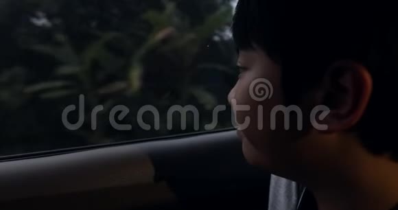 小亚洲男孩坐着车透过窗户看着视频的预览图