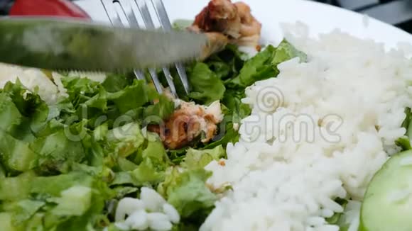 刀将鸡肉串切在沙拉和米饭的盘子上视频的预览图